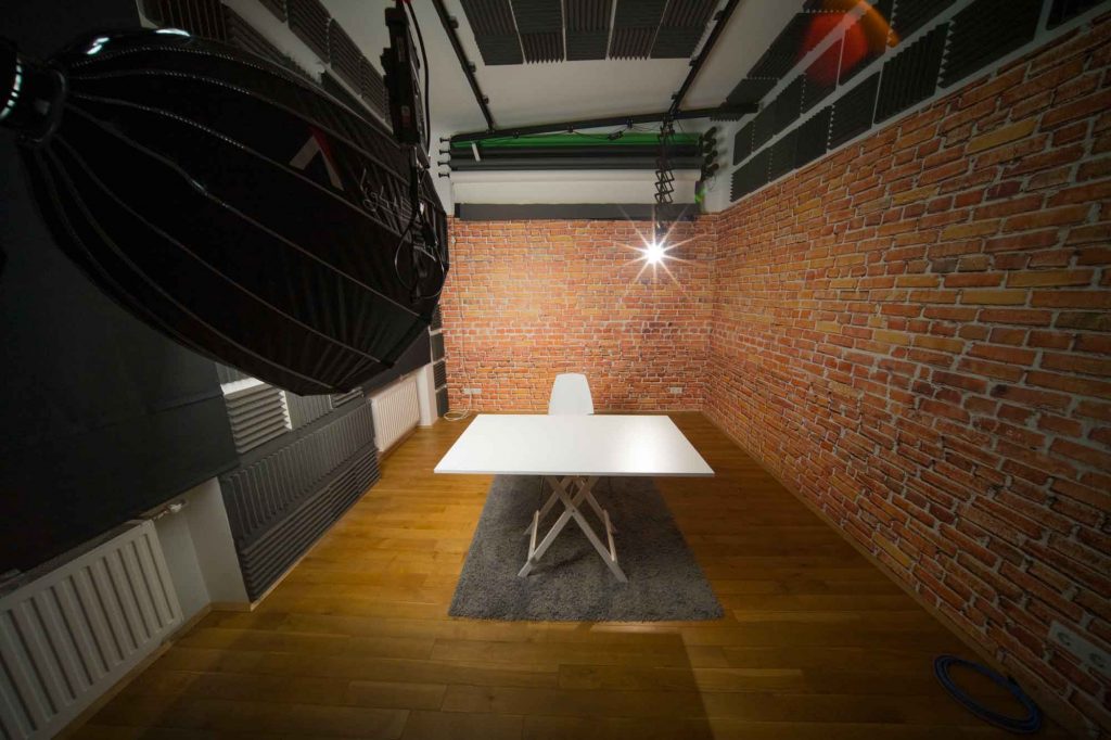 Foto- und Videostudio mit weißem Tisch, Sessel und Lampe
