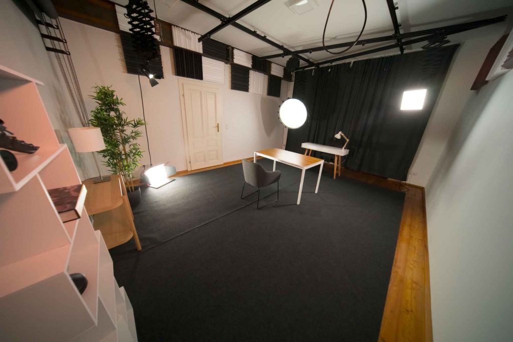 Foto- und Videostudio mit Lampen und Holztisch in der Mitte